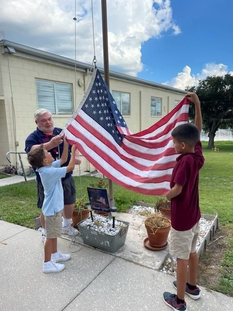 Quartermaster getting students to help raise the flag after flag pole repair.